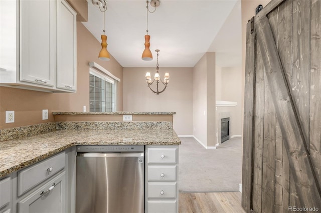 kitchen with dishwasher, white cabinetry, light stone countertops, decorative light fixtures, and a barn door