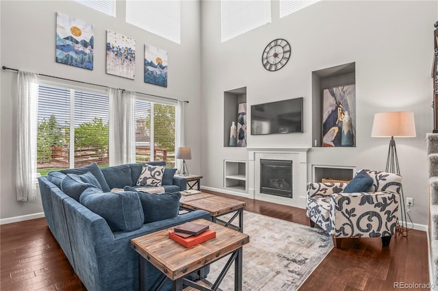 living room featuring a fireplace, baseboards, a high ceiling, and hardwood / wood-style floors