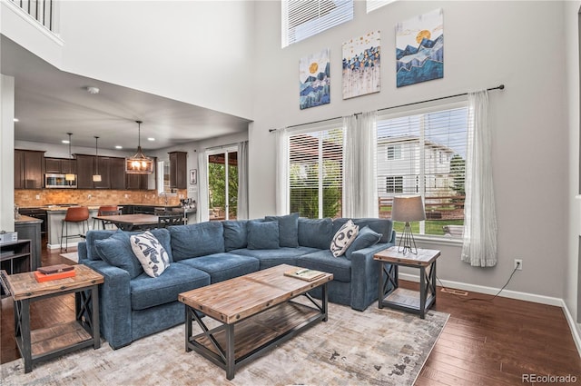 living room featuring baseboards, a high ceiling, light wood-type flooring, and visible vents