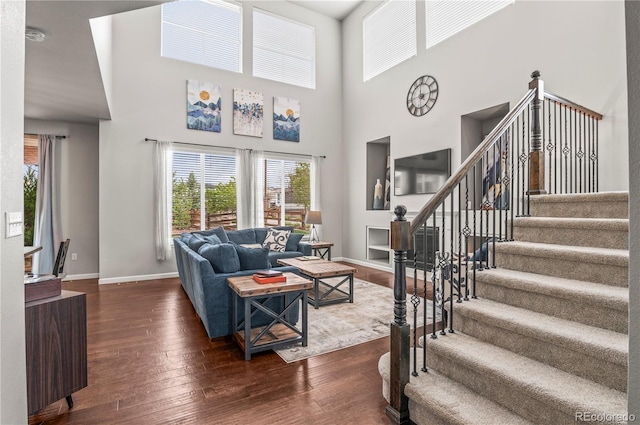 living room with stairs, baseboards, a high ceiling, and dark wood-type flooring