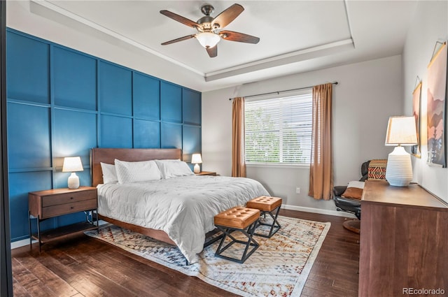 bedroom featuring baseboards, a ceiling fan, a raised ceiling, and hardwood / wood-style flooring