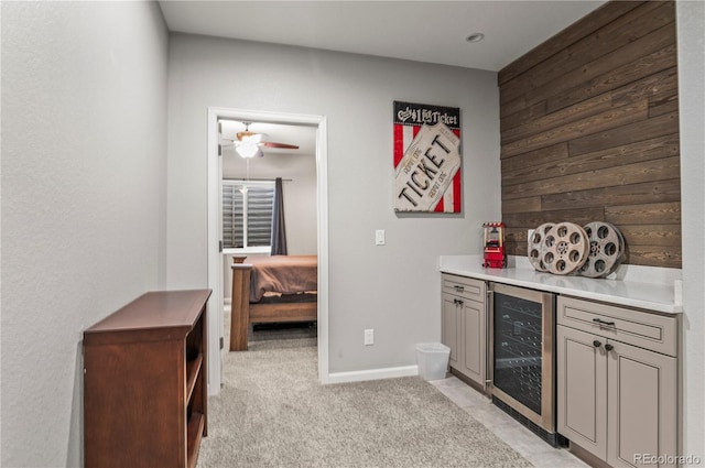 bar with a ceiling fan, baseboards, wooden walls, wine cooler, and light carpet