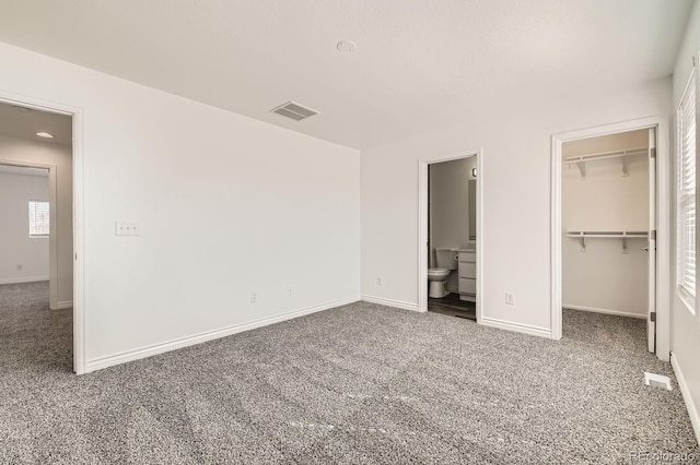 unfurnished bedroom with baseboards, carpet, and a spacious closet