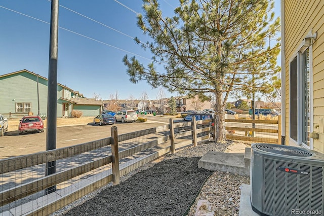 view of yard with a residential view, central AC unit, and fence