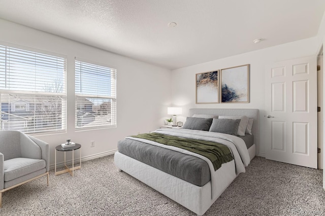 bedroom featuring carpet, baseboards, and a textured ceiling