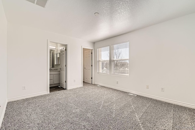 unfurnished bedroom with visible vents, ensuite bathroom, a textured ceiling, carpet floors, and baseboards