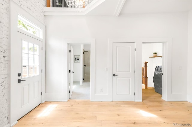 230 E Ellsworth Ave, Denver, CO 80209 - foyer entrance with light wood-style floors, washer / clothes dryer, a chandelier, a high ceiling, and baseboards