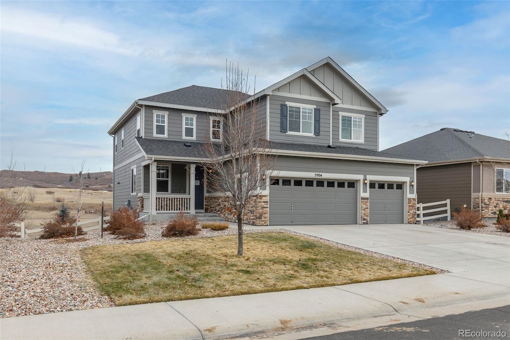 craftsman-style home featuring covered porch, a front yard, and a garage