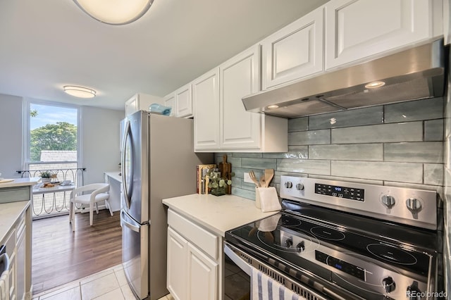 937 N Clarkson St Unit 405, Denver, CO 80218 - kitchen with appliances with stainless steel finishes, under cabinet range hood, white cabinetry, light countertops, and tasteful backsplash
