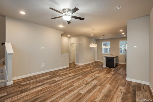 unfurnished living room with ceiling fan, dark hardwood / wood-style flooring, and sink