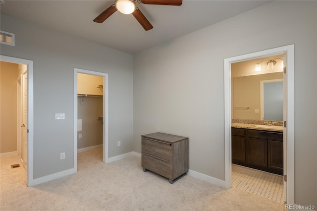 unfurnished bedroom with light carpet, connected bathroom, a spacious closet, and a closet