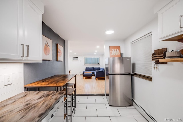 20 S Logan St Unit 104, Denver, CO 80209 - kitchen with freestanding refrigerator, a baseboard heating unit, white cabinets, light tile patterned floors, and decorative backsplash