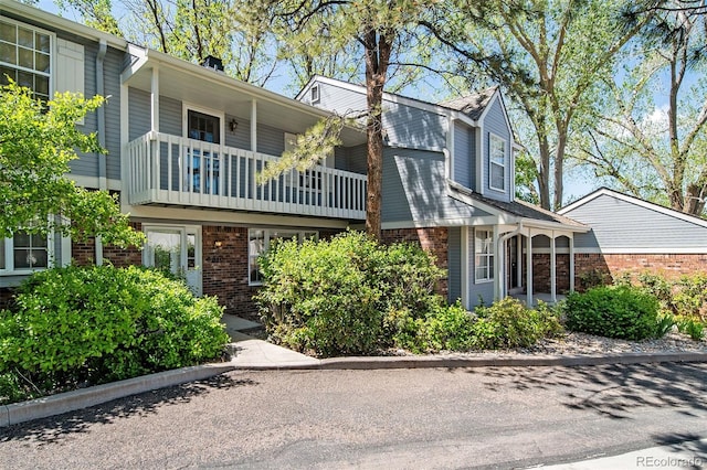 view of front of home featuring a balcony and brick siding