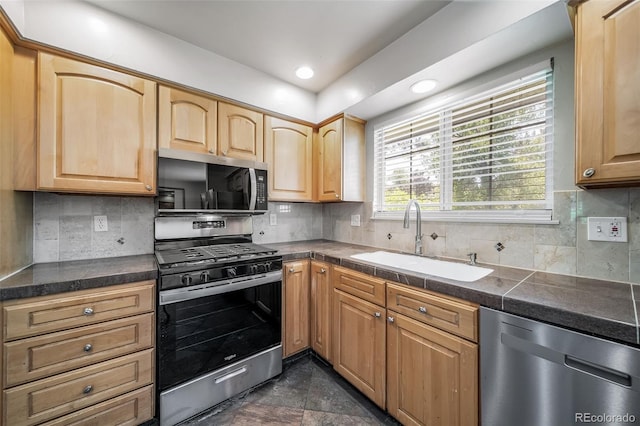 kitchen featuring stainless steel appliances, a sink, backsplash, dark countertops, and recessed lighting