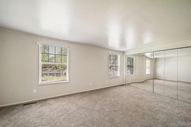 unfurnished bedroom featuring multiple windows, crown molding, light colored carpet, and baseboards