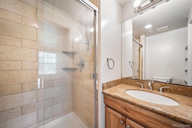 bathroom with toilet, a stall shower, and vanity