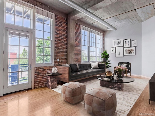 living area featuring brick wall, plenty of natural light, and wood finished floors