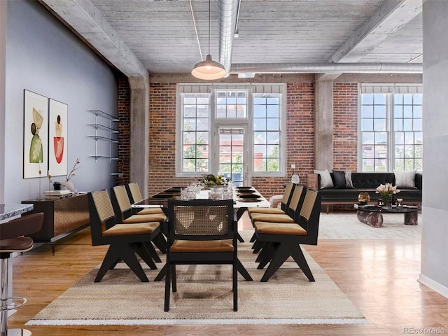 dining area with brick wall and wood finished floors