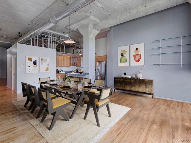 dining space with light wood finished floors and a towering ceiling