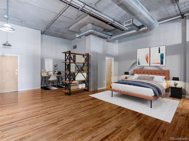 bedroom featuring a high ceiling, wood finished floors, and visible vents