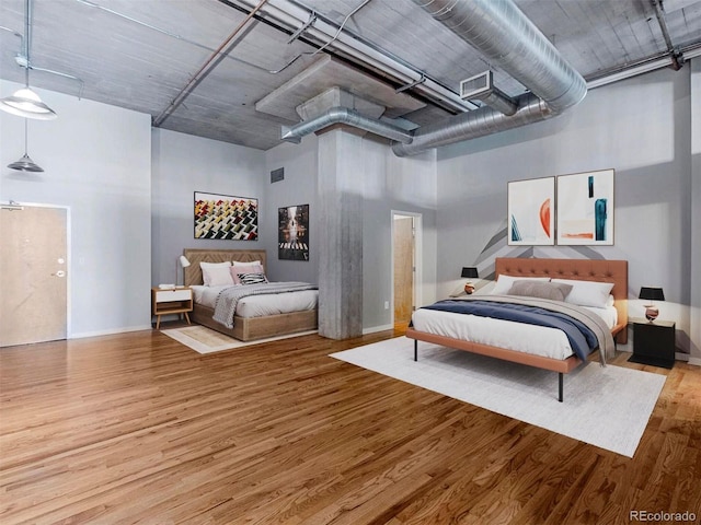 bedroom featuring visible vents, wood finished floors, and a towering ceiling