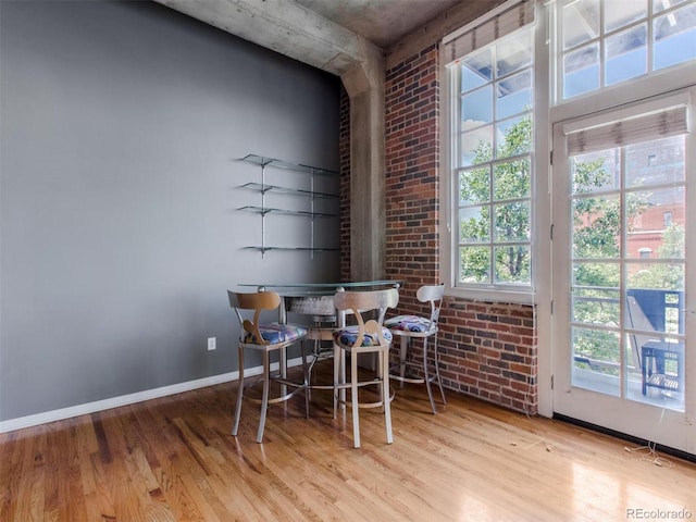 dining room with baseboards, brick wall, and wood finished floors