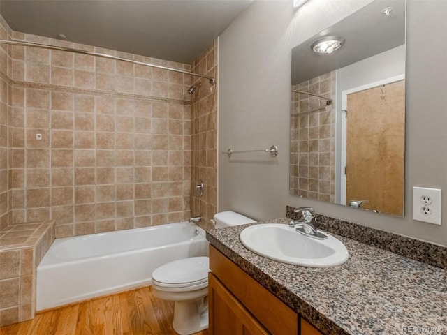 full bath with shower / bath combination, vanity, toilet, and wood finished floors