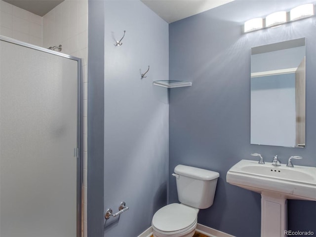 bathroom with a sink, a shower stall, toilet, and baseboards