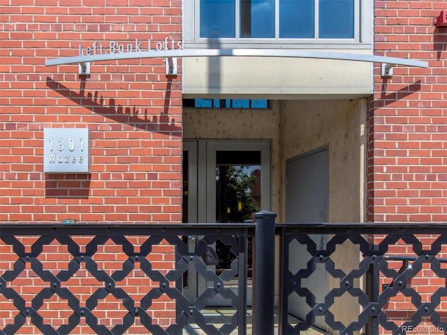 doorway to property with brick siding and fence