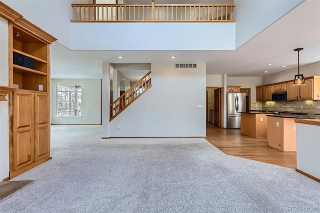 kitchen with decorative backsplash, stainless steel appliances, pendant lighting, a high ceiling, and light hardwood / wood-style floors