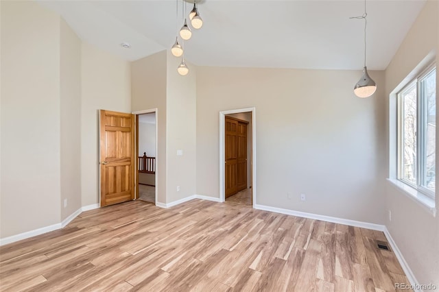 empty room featuring light hardwood / wood-style flooring and high vaulted ceiling