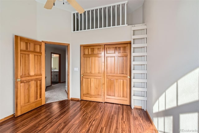 interior space with ceiling fan, dark hardwood / wood-style flooring, and a high ceiling