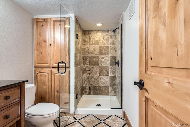 bathroom featuring a textured ceiling, toilet, and a shower with shower door