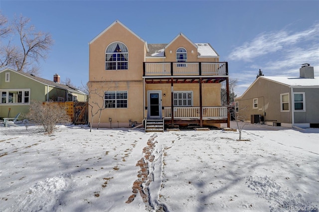 view of front of house featuring a porch, central air condition unit, a balcony, and stucco siding