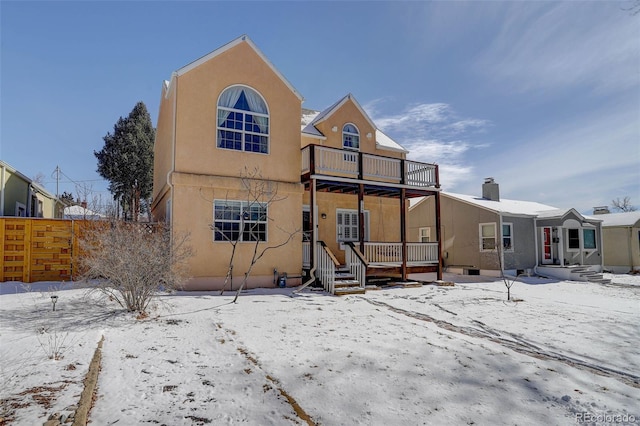 snow covered house with a balcony and stucco siding