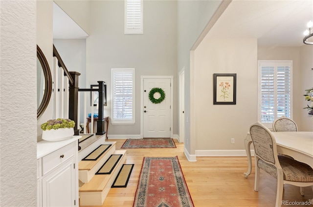 entrance foyer with light wood-type flooring, visible vents, stairs, and baseboards