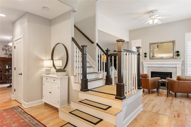 stairs with ceiling fan, baseboards, wood finished floors, and a tile fireplace