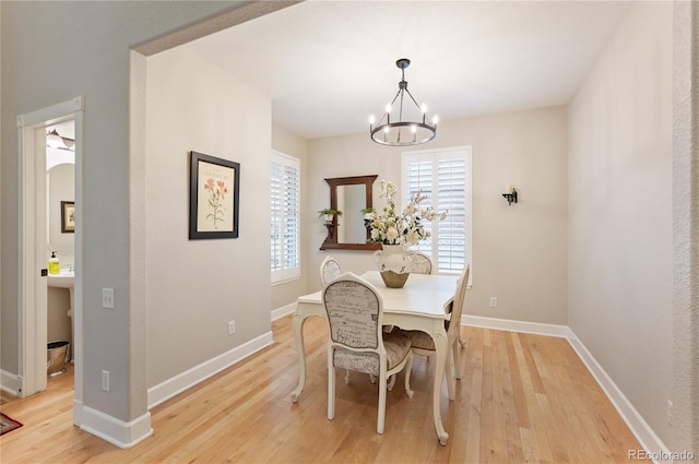 dining area featuring baseboards, an inviting chandelier, and light wood-style floors