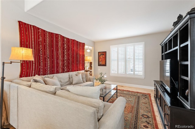 living area featuring baseboards and light wood finished floors