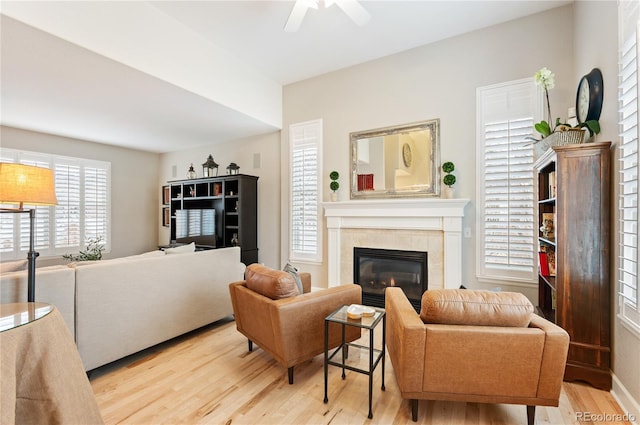 living room featuring a fireplace, a ceiling fan, and wood finished floors