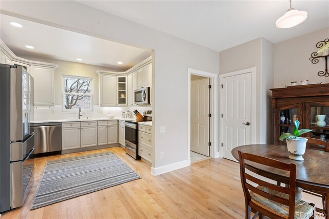 kitchen featuring light wood-type flooring, appliances with stainless steel finishes, light countertops, and a sink