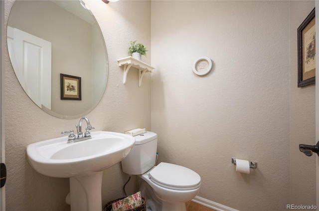 bathroom featuring a textured wall, a sink, and toilet