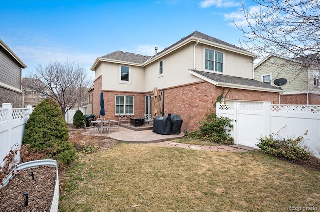 rear view of house featuring brick siding, a patio, a fenced backyard, a yard, and stucco siding