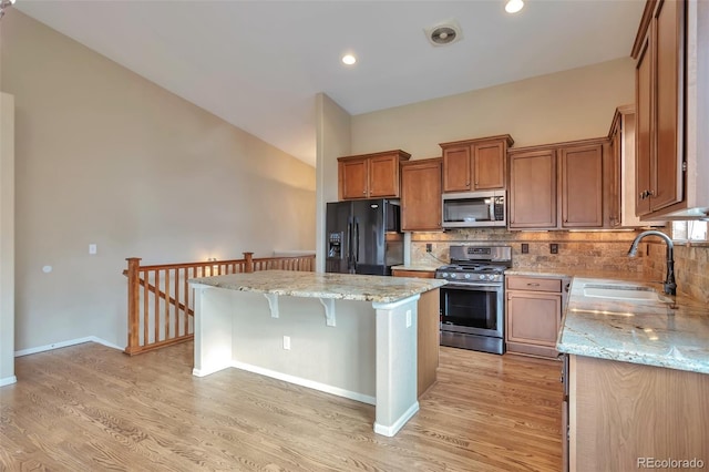 kitchen featuring stainless steel appliances, a sink, a kitchen island, light wood-type flooring, and recessed lighting