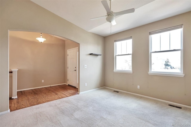 unfurnished room with carpet, arched walkways, ceiling fan, baseboards, and vaulted ceiling