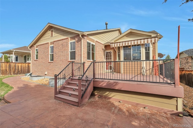 back of house featuring fence, brick siding, and a patio