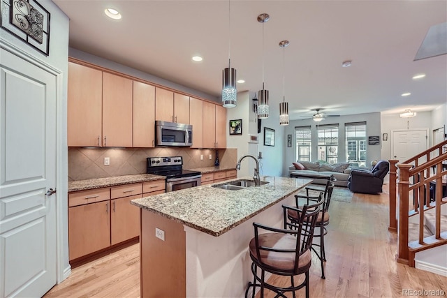 kitchen with appliances with stainless steel finishes, light stone countertops, sink, and light brown cabinets