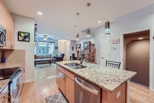 kitchen with pendant lighting, sink, appliances with stainless steel finishes, a center island with sink, and light brown cabinets