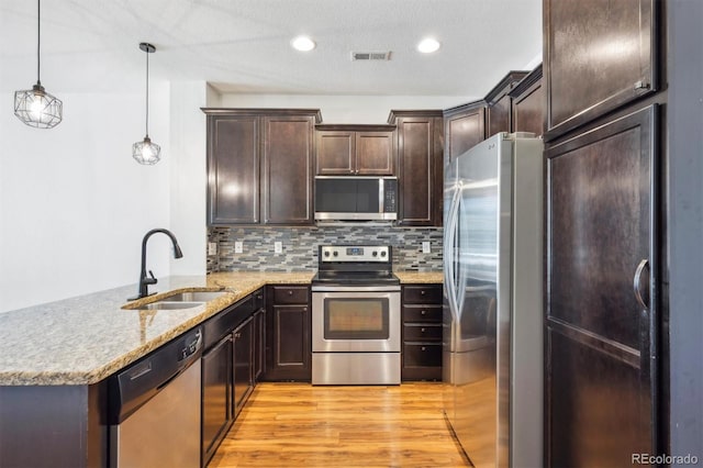 16285 W 62nd Ln Unit C, Arvada, CO 80403 - kitchen featuring appliances with stainless steel finishes, a sink, a peninsula, light wood-style flooring, and dark brown cabinetry
