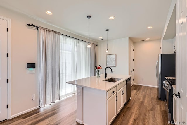 24374 E 42nd Ave, Aurora, CO 80019 - kitchen with a sink, appliances with stainless steel finishes, white cabinets, wood finished floors, and a center island with sink